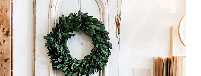 Boxwood wreath hanging on chippy white door 