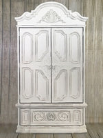 Large, ornate and heavily detailed armoire painted in Rethunk Junk by Laura Paint in the color Cotton, which is a warm white.