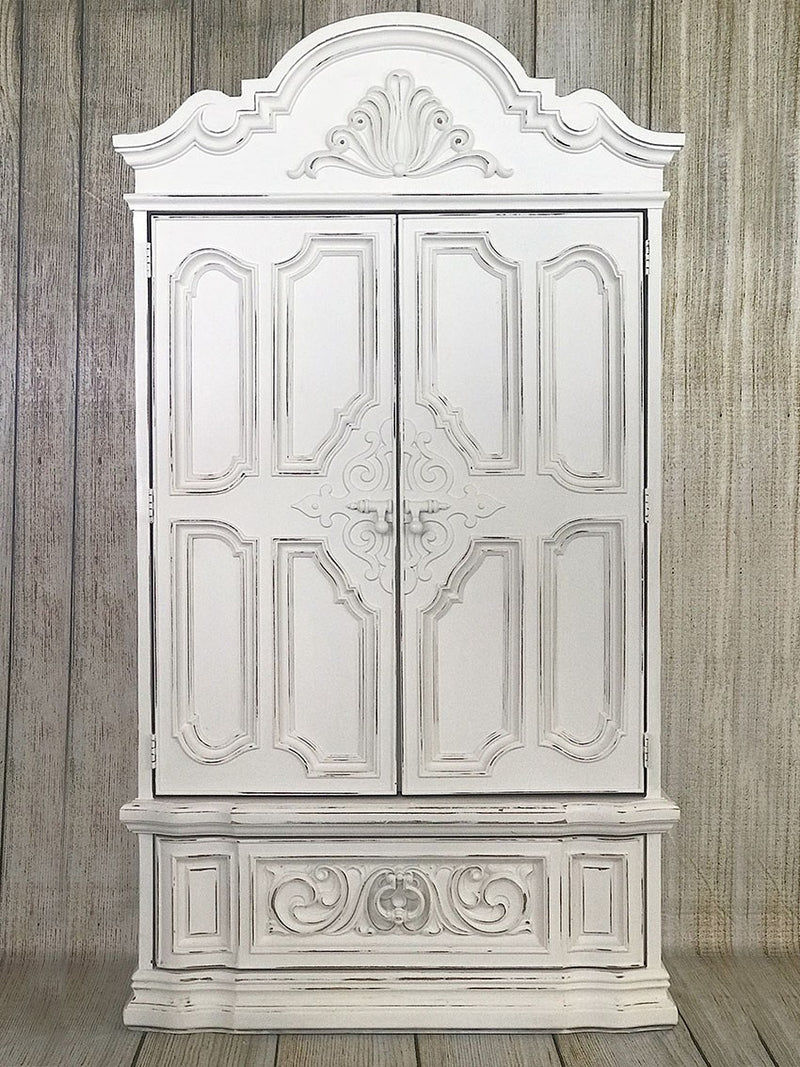 Large, ornate and heavily detailed armoire painted in Rethunk Junk by Laura Paint in the color Cotton, which is a warm white.